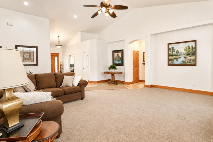 Spacious living area featuring vaulted ceilings, recessed lighting, and a ceiling fan