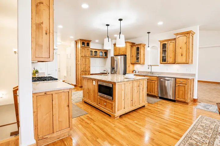Kitchen featuring a central island with built-in microwave, wood-finish flooring, recessed lighting, and stainless steel appliances
