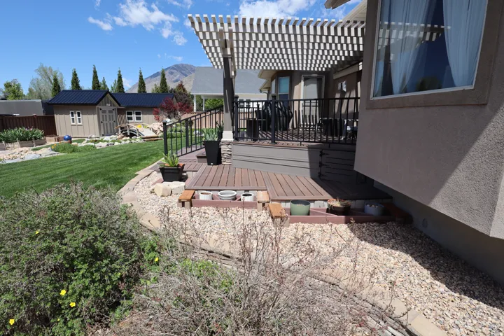 Expansive backyard featuring a manicured lawn, established landscaping, and two detached storage sheds with dark metal roofs