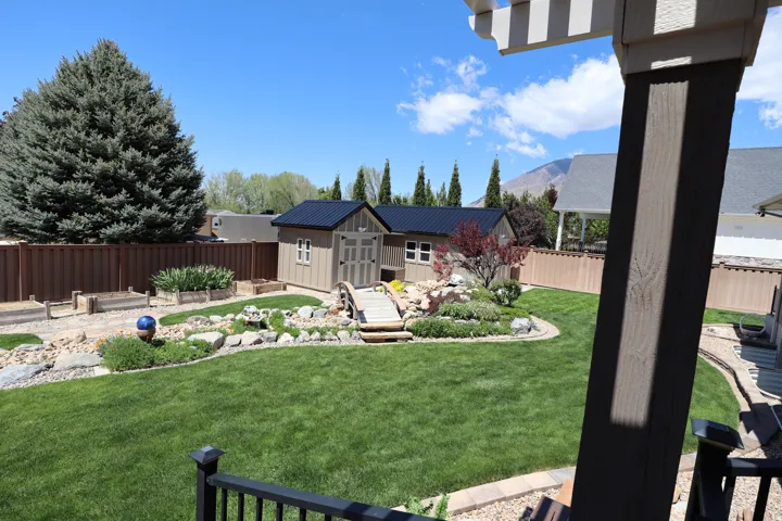Expansive green lawn with a dedicated garden shed featuring a dark metal roof
