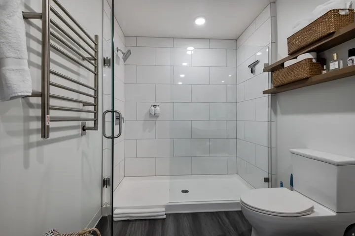 Bathroom featuring a towel warming rack, radiator heating unit, a shower stall, and dark wood-style floors