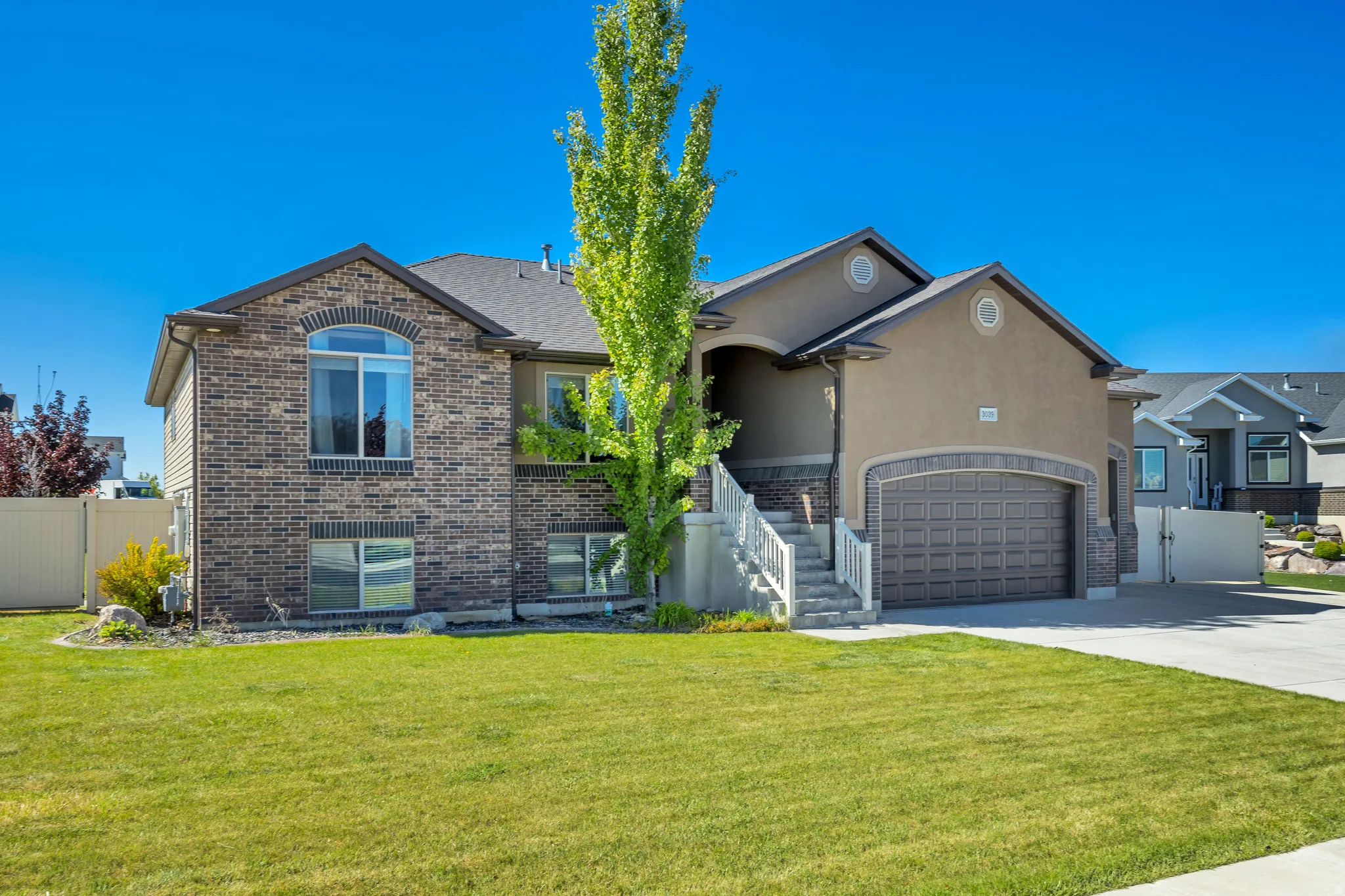 View of front facade with concrete driveway, stucco siding, an attached garage, brick siding, and a gate
