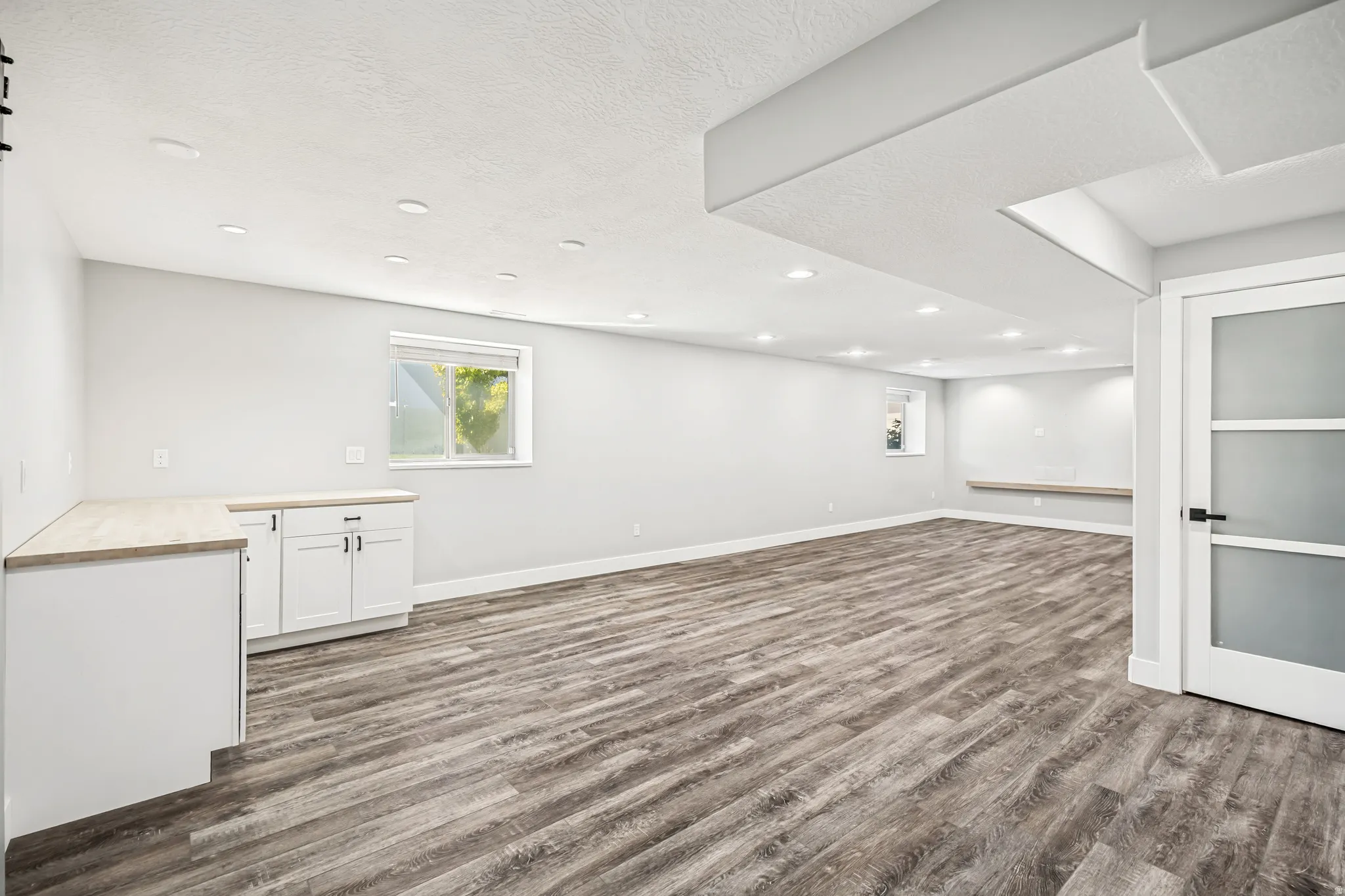 Below grade area featuring dark wood-type flooring, a textured ceiling, and recessed lighting