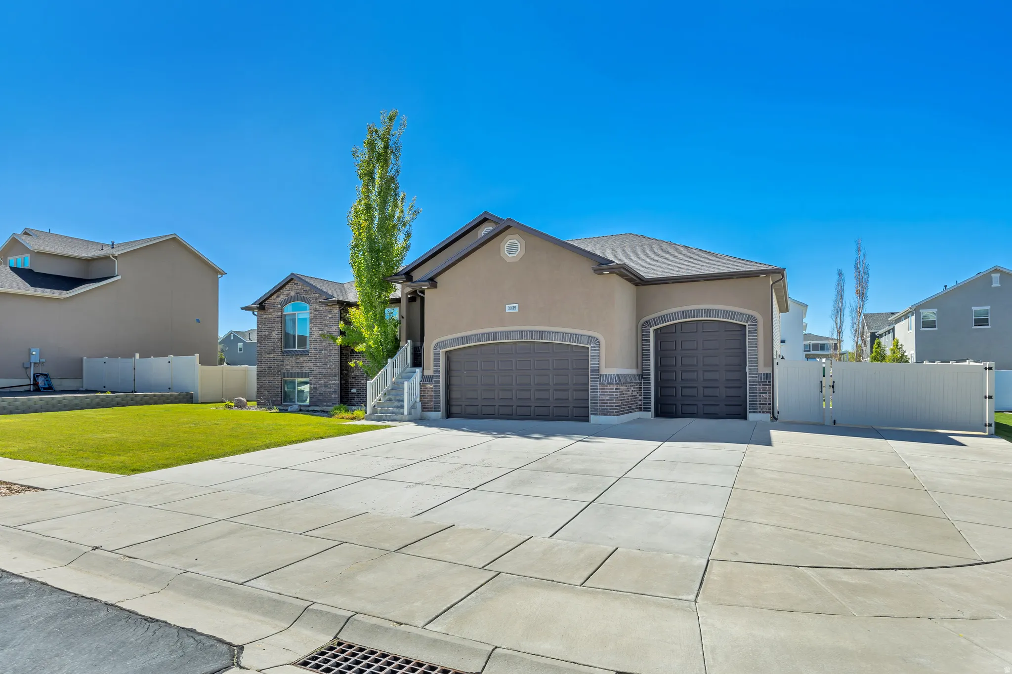 View of front of property featuring a gate, an attached garage, stucco siding, driveway, and stone siding