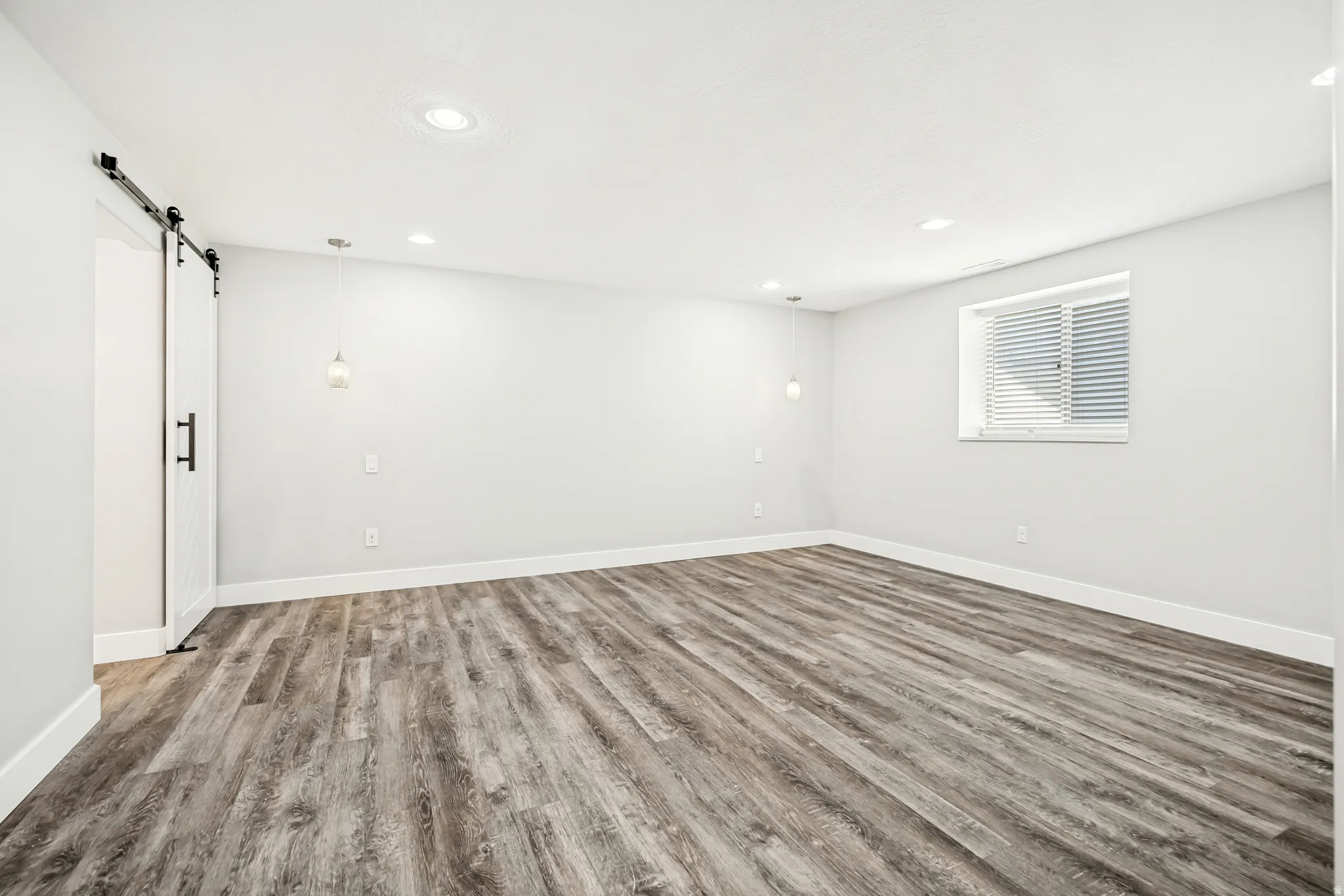 Unfurnished room featuring a barn door, light wood finished floors, and recessed lighting