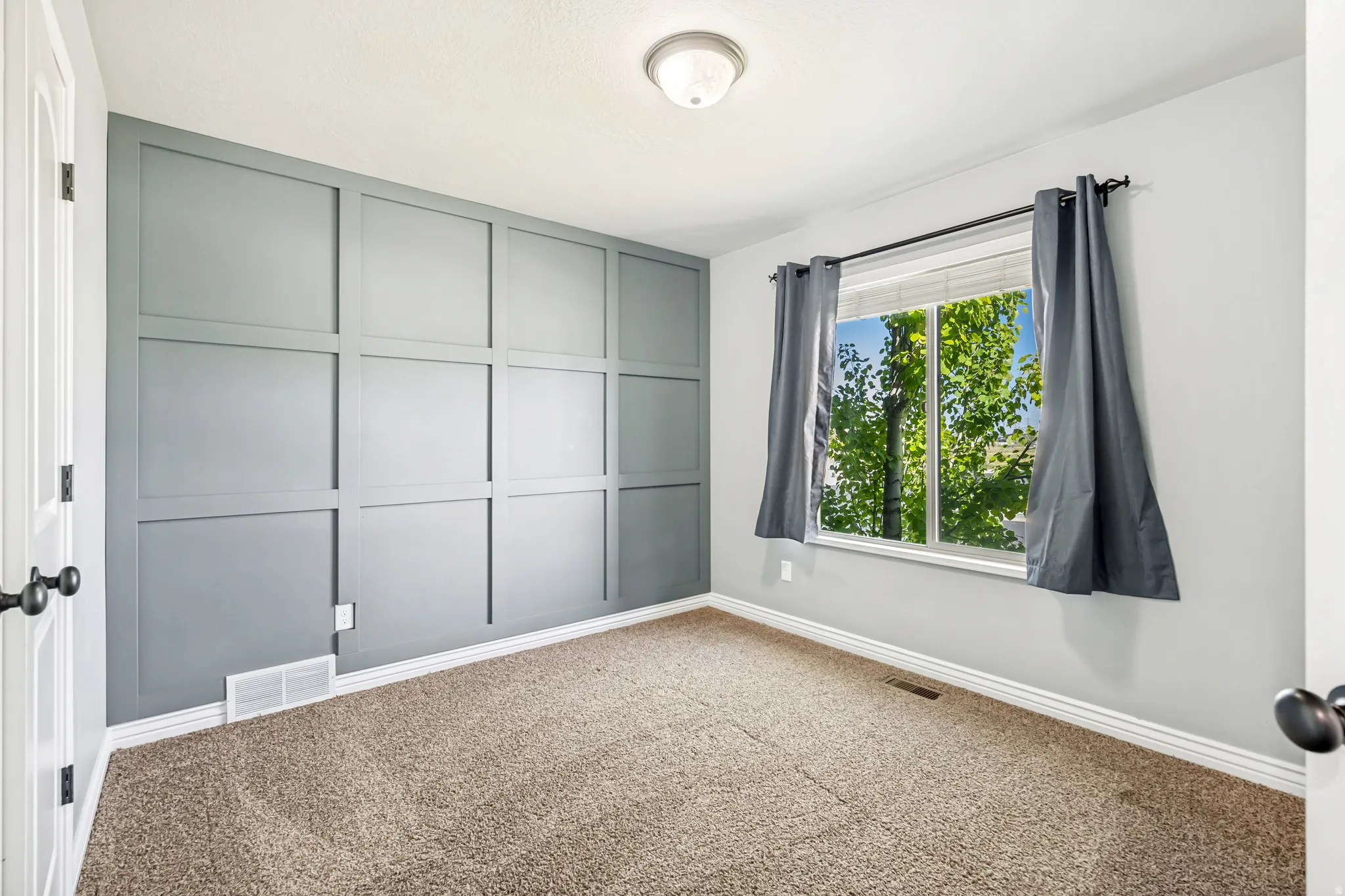 Carpeted empty room featuring baseboards and a decorative wall