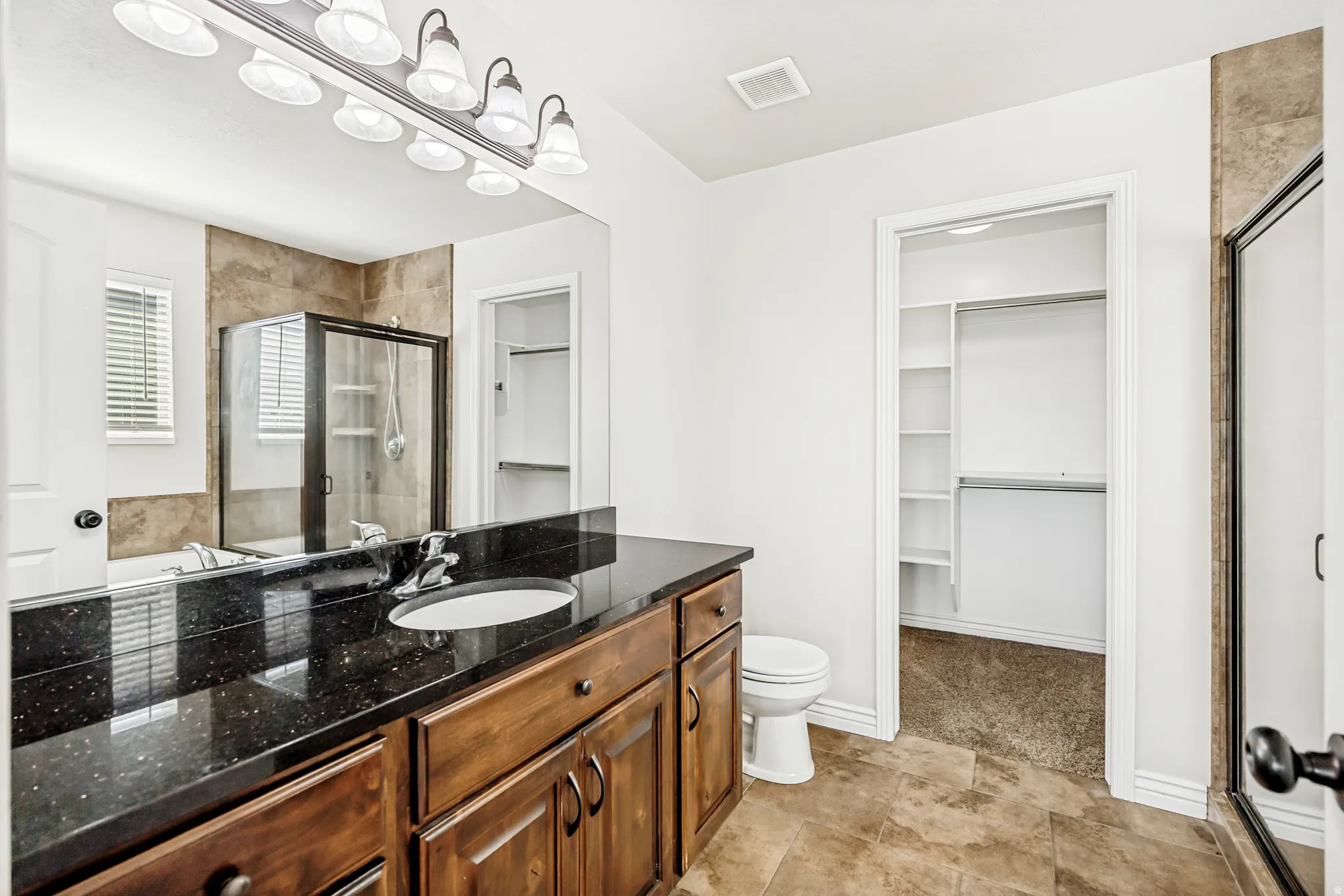 Bathroom featuring a walk in closet, a shower stall, and vanity