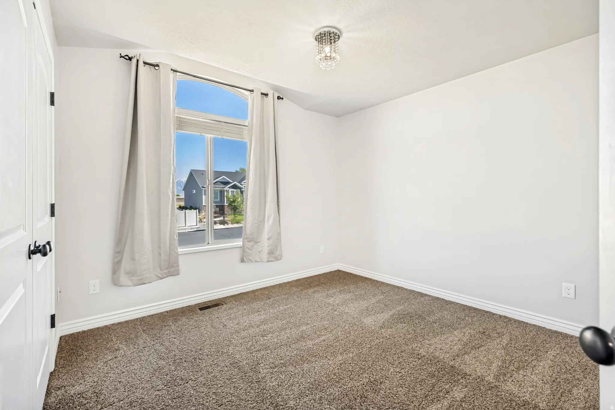 Spare room featuring dark carpet and baseboards