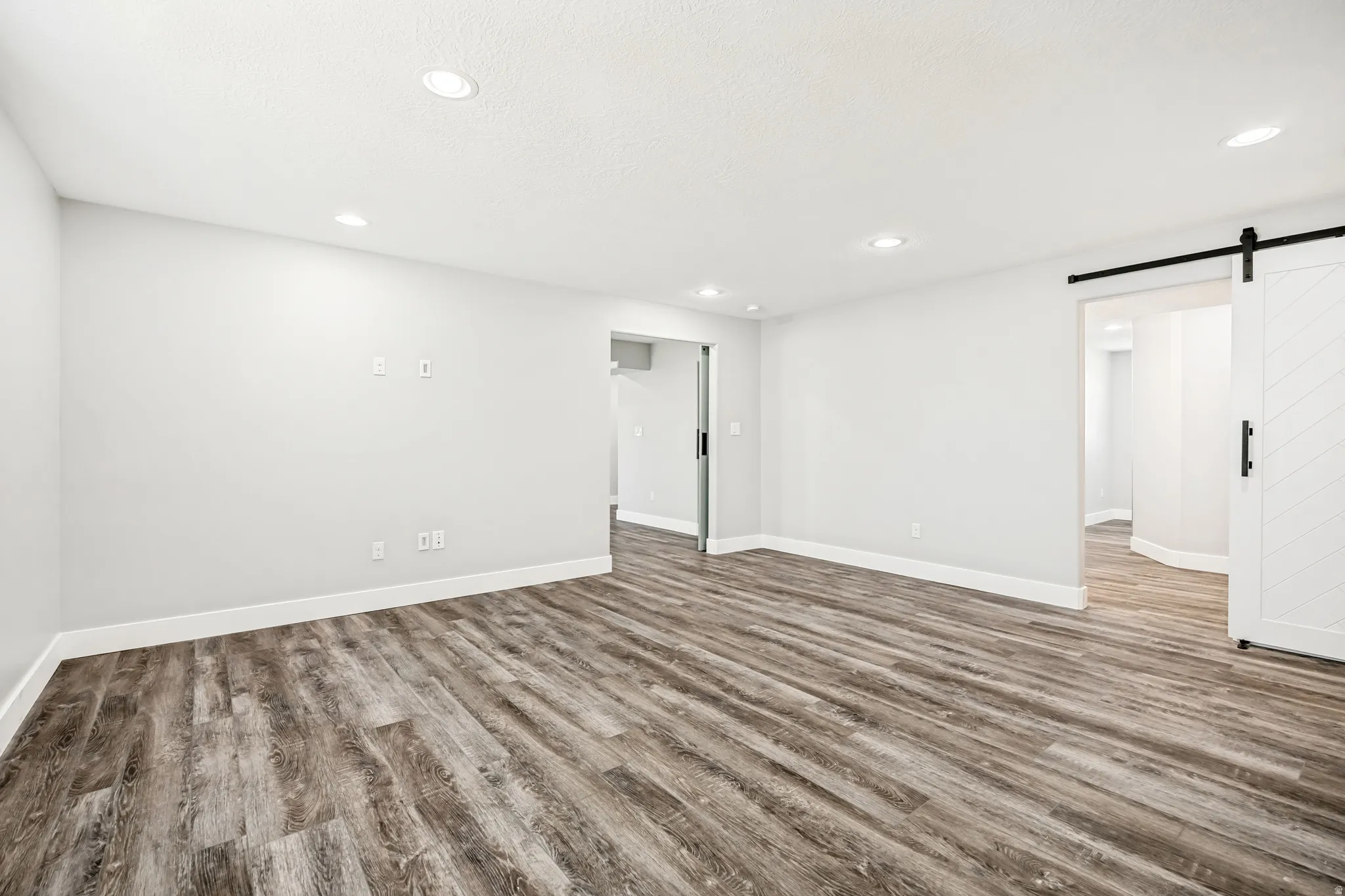 Unfurnished room with a barn door, wood finished floors, and recessed lighting