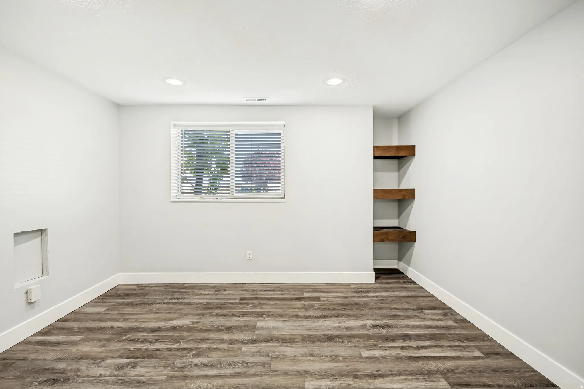 Empty room with dark wood-type flooring and recessed lighting