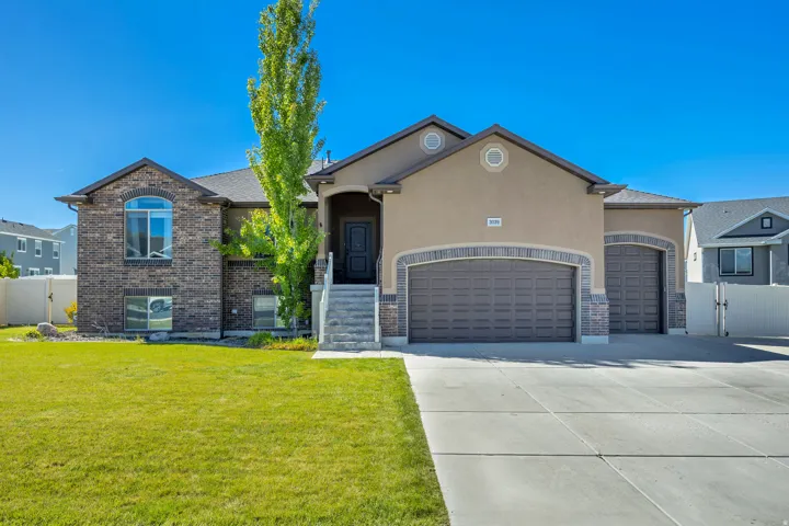 View of front of home featuring an attached garage, a gate, stucco siding, and driveway
