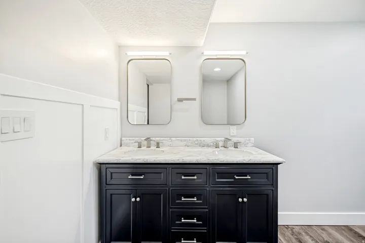 Bathroom featuring double vanity, wood finished floors, and a textured ceiling
