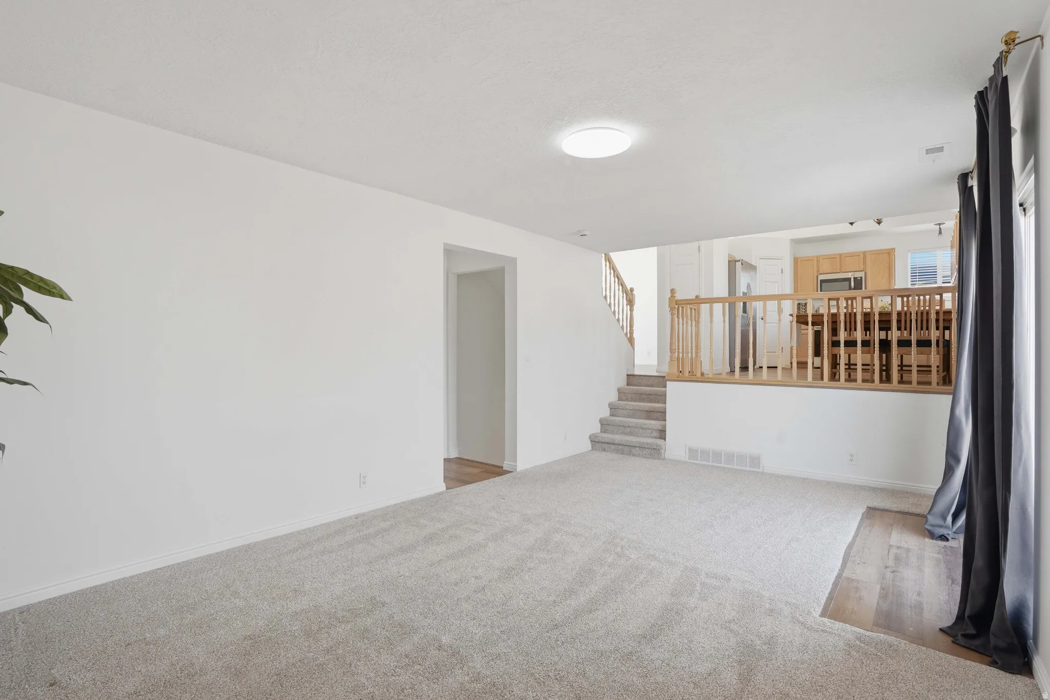 Unfurnished living room with stairway and carpet flooring