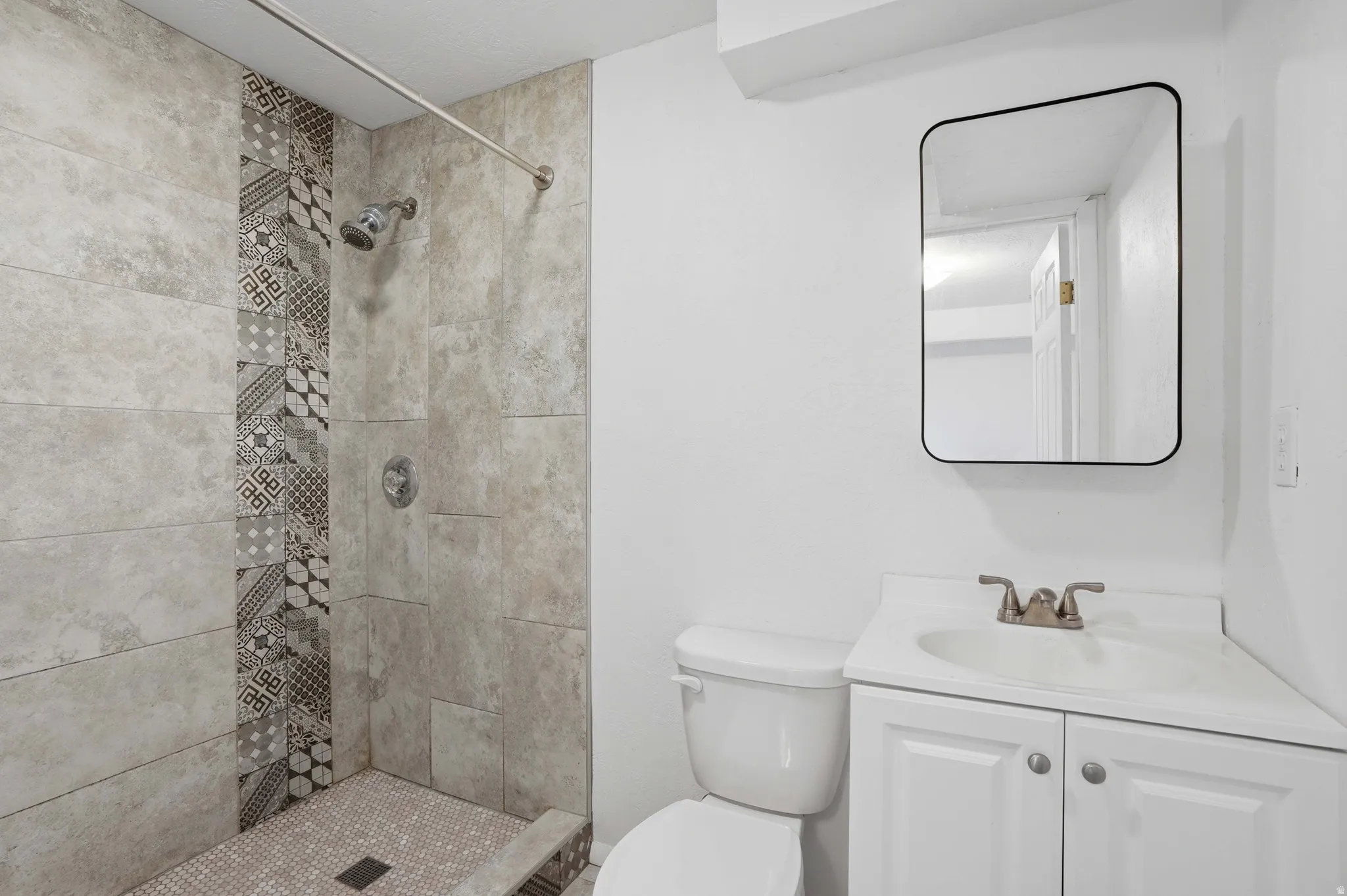 Bathroom featuring tiled shower and vanity