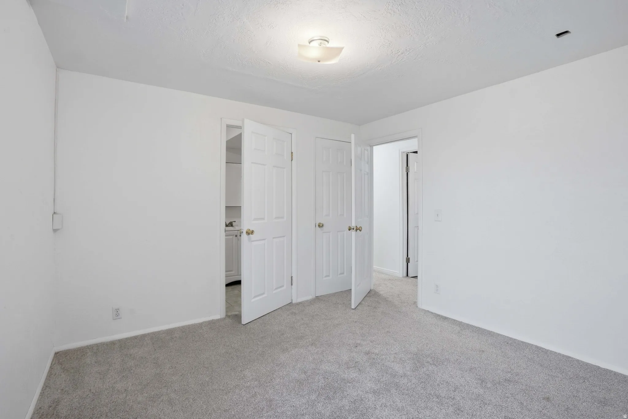 Unfurnished bedroom with light carpet and a textured ceiling