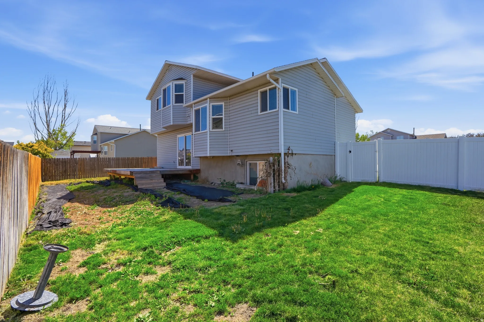 Rear view of house featuring a fenced backyard, a wooden deck, and a gate