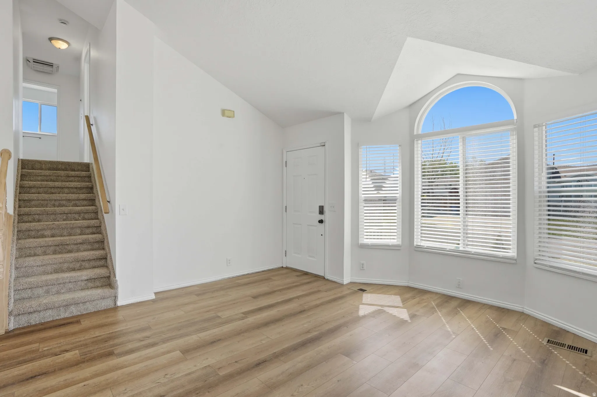 Foyer featuring vaulted ceiling and light wood-style floors