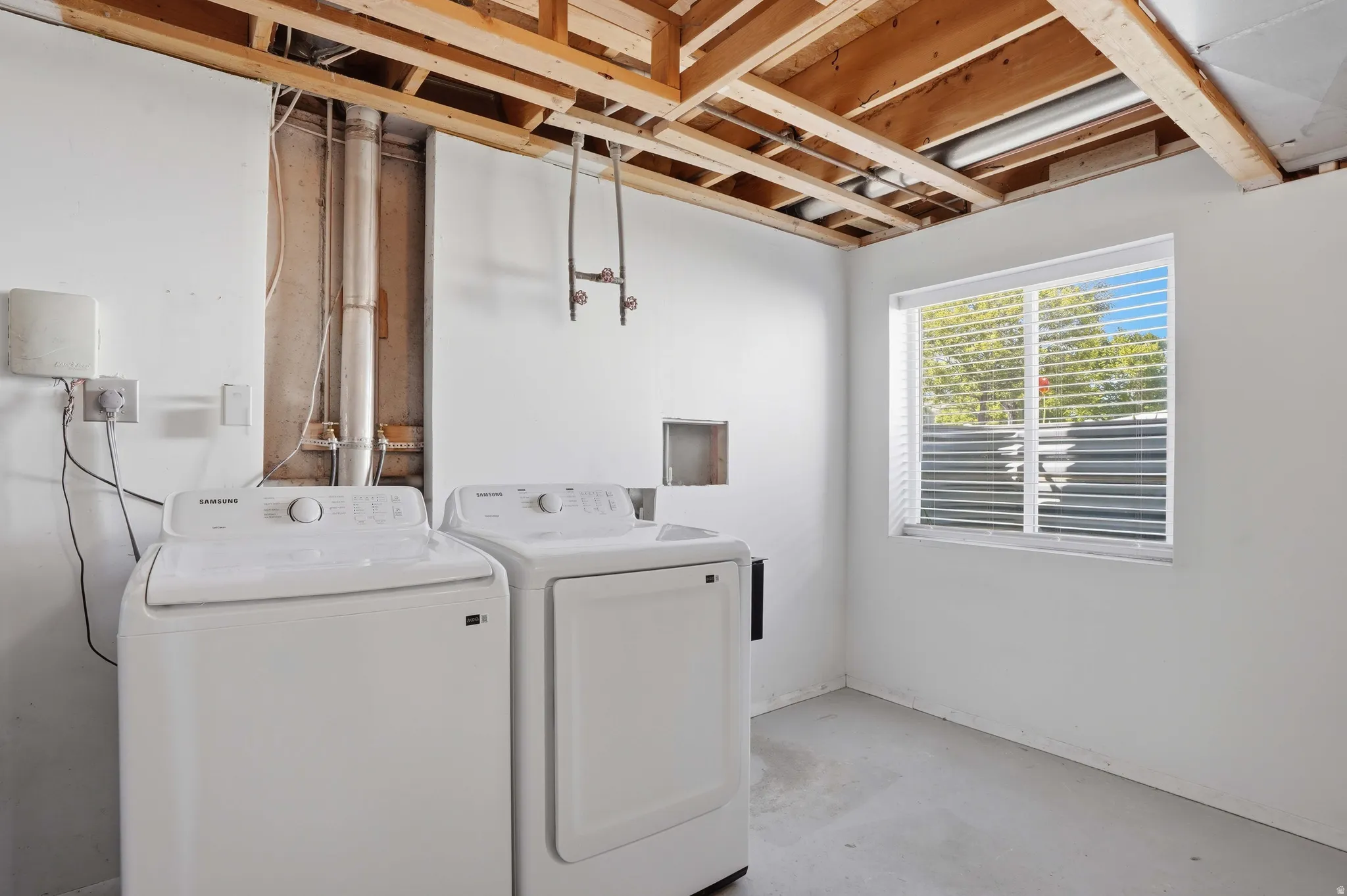 Laundry room featuring unfinished concrete flooring and independent washer and dryer