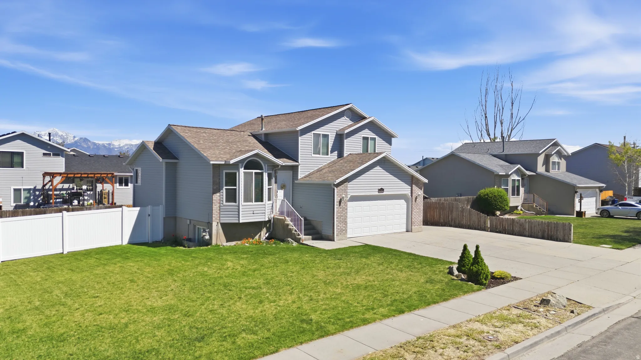 View of front facade with a residential view, driveway, brick siding, and an attached garage