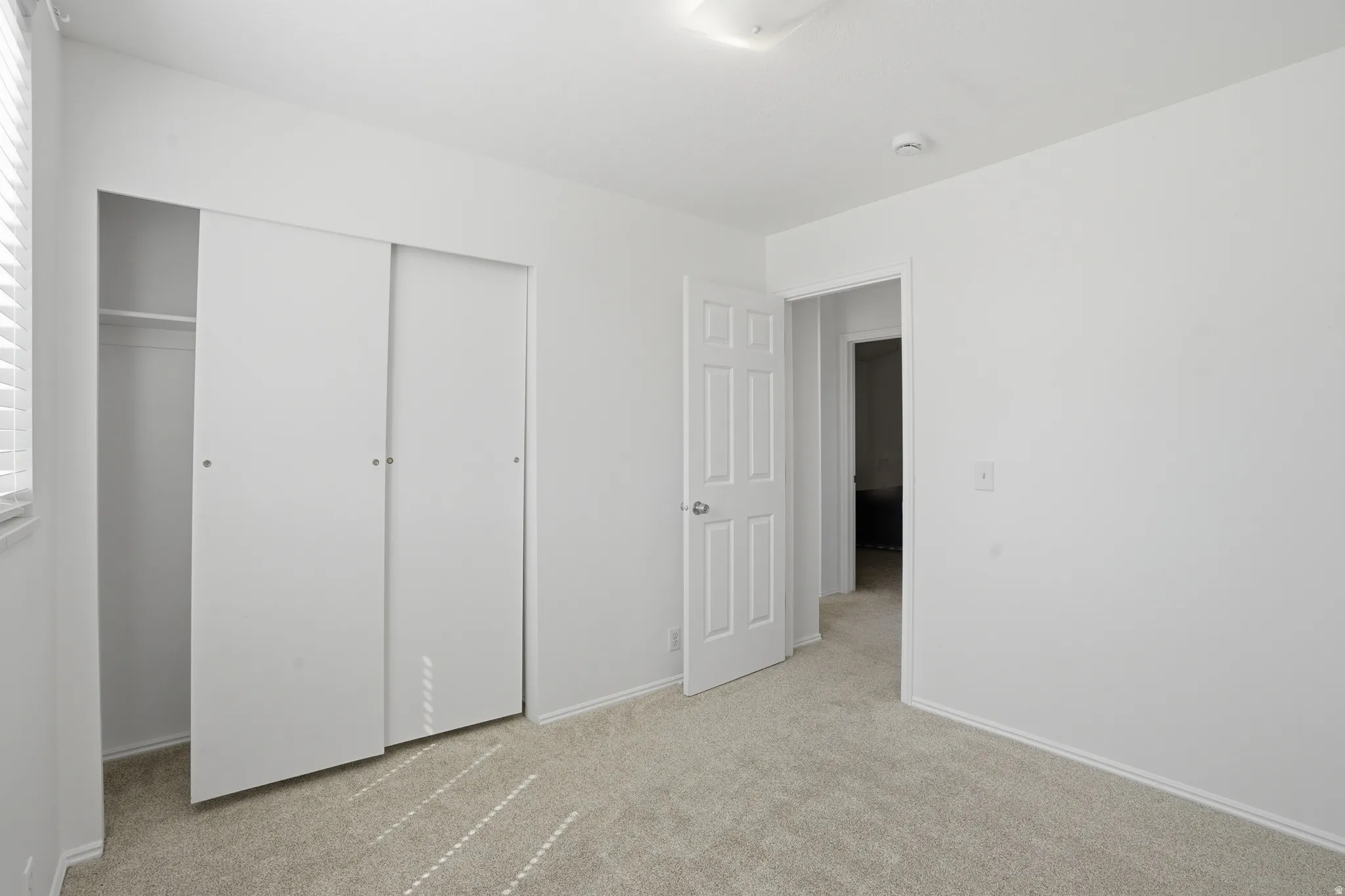 Unfurnished bedroom with light carpet and a closet