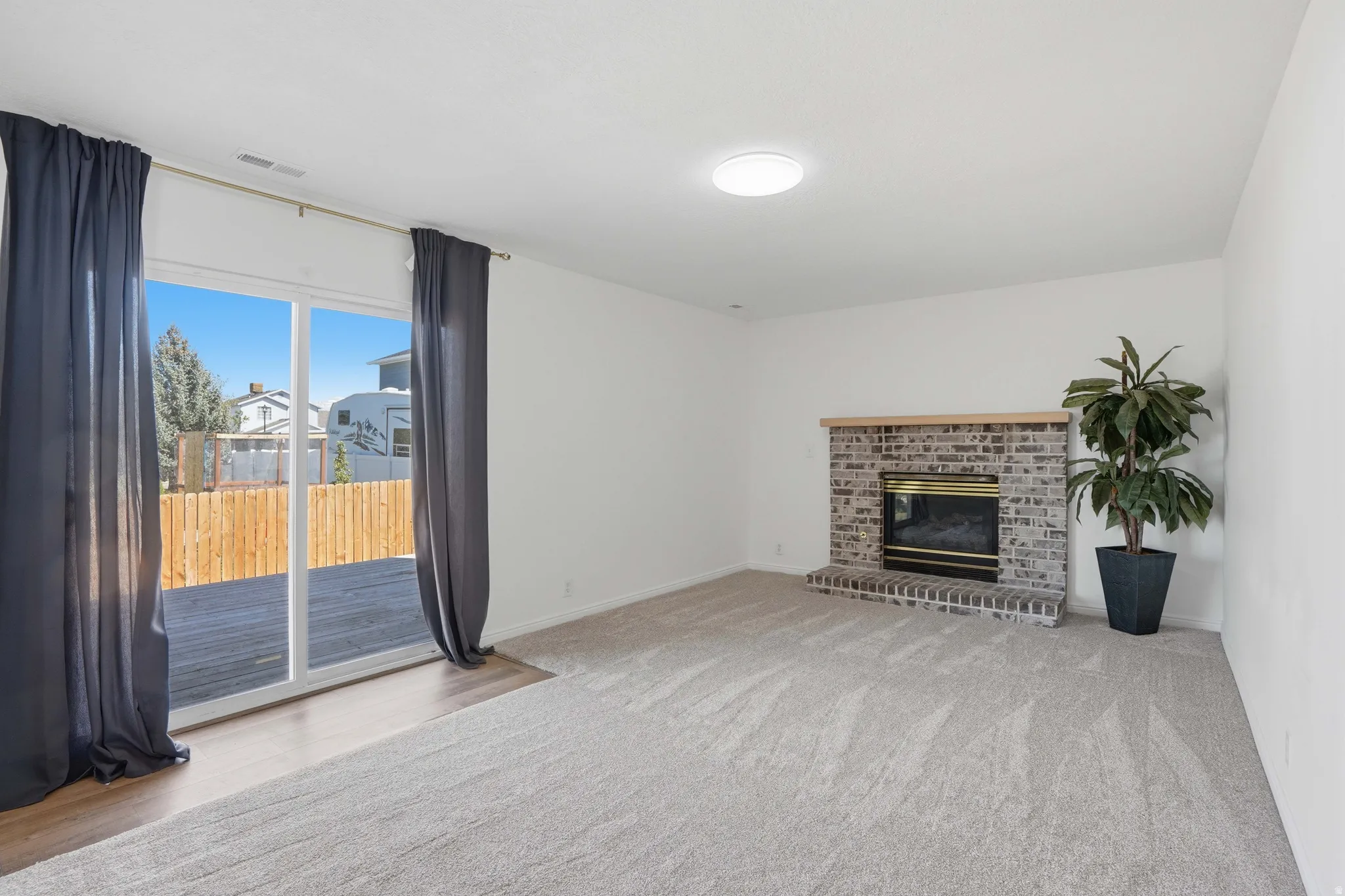 Unfurnished living room featuring a brick fireplace and light carpet