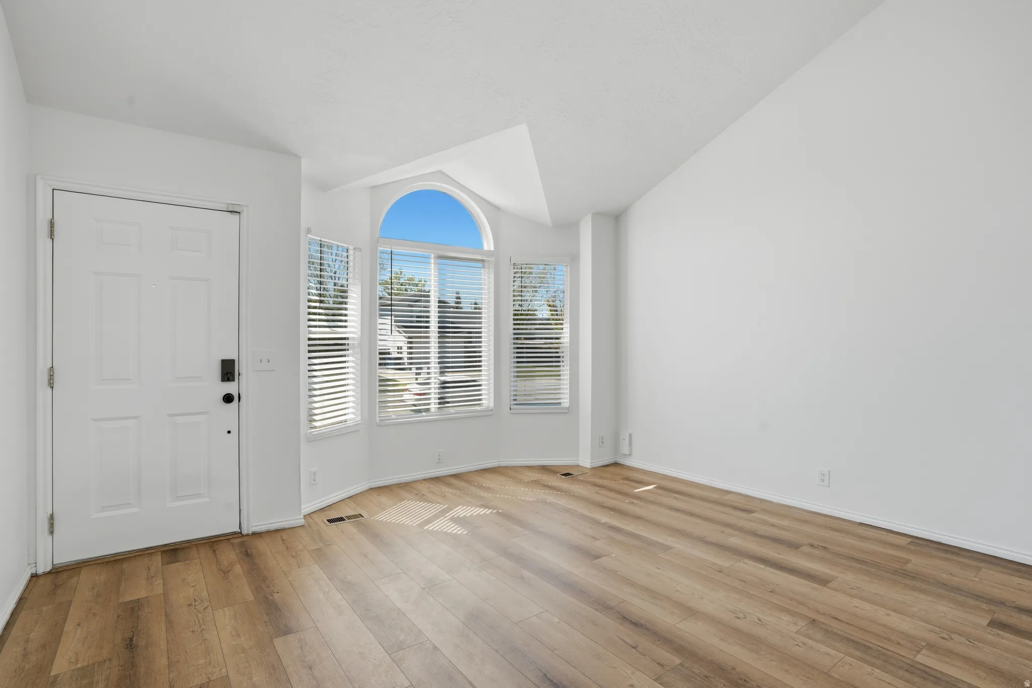 Entryway with lofted ceiling and light wood-style floors