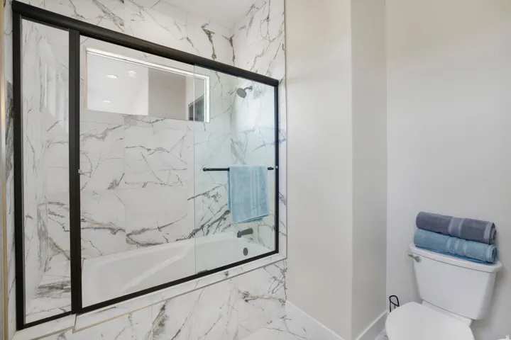 Full bathroom with toilet and enclosed tub / shower combo