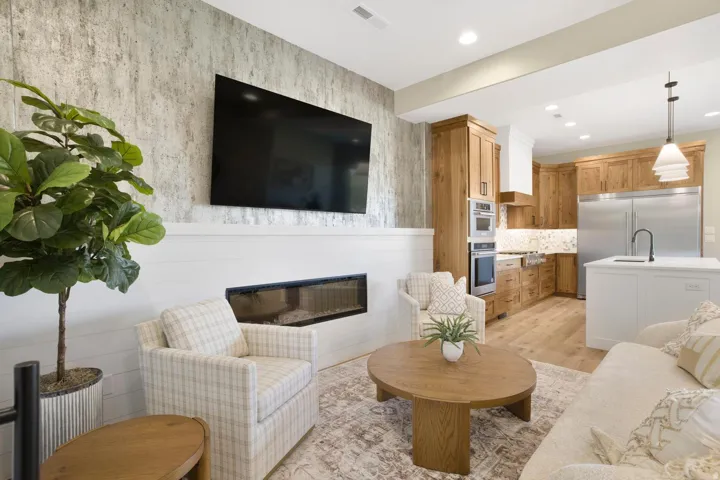 Living room with light wood finished floors, a glass covered fireplace, and recessed lighting