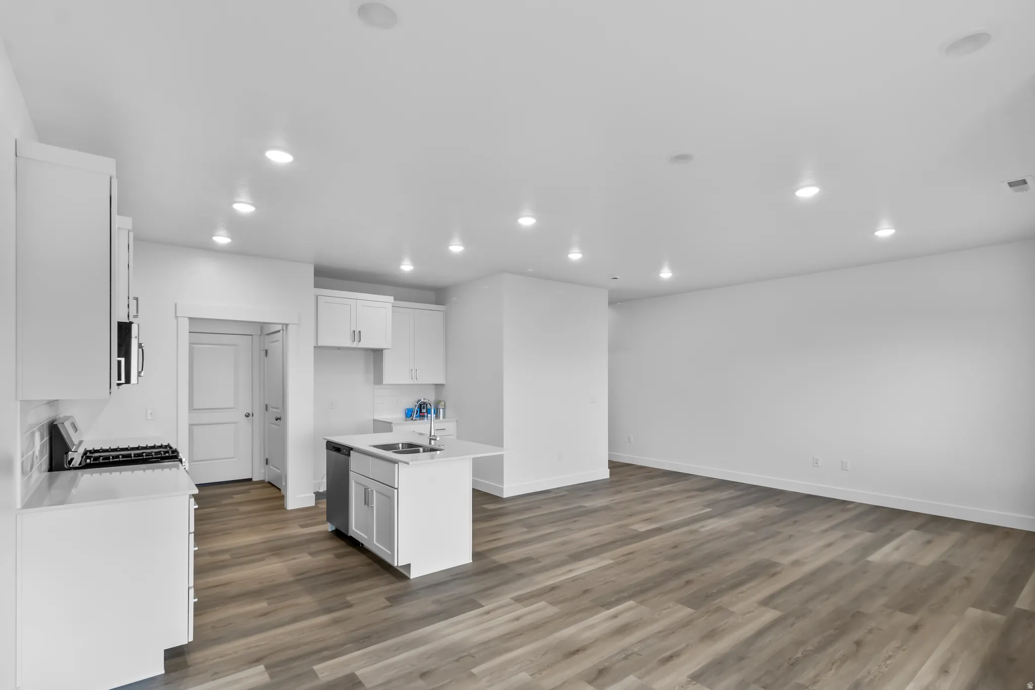 Kitchen with white cabinetry, recessed lighting, a center island with sink, dark wood finished floors, and open floor plan