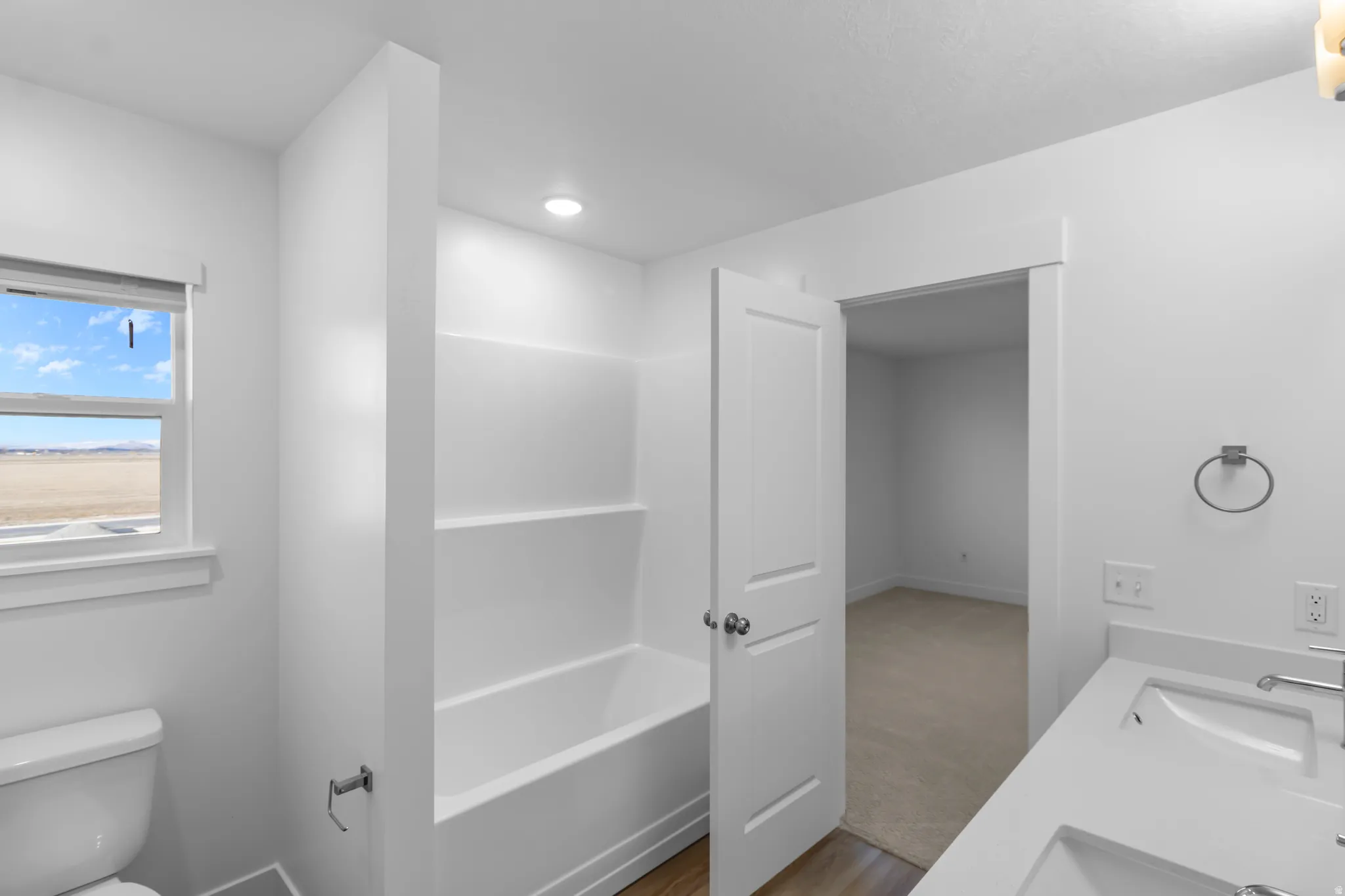 Bathroom with double vanity, a bath, and light wood finished floors