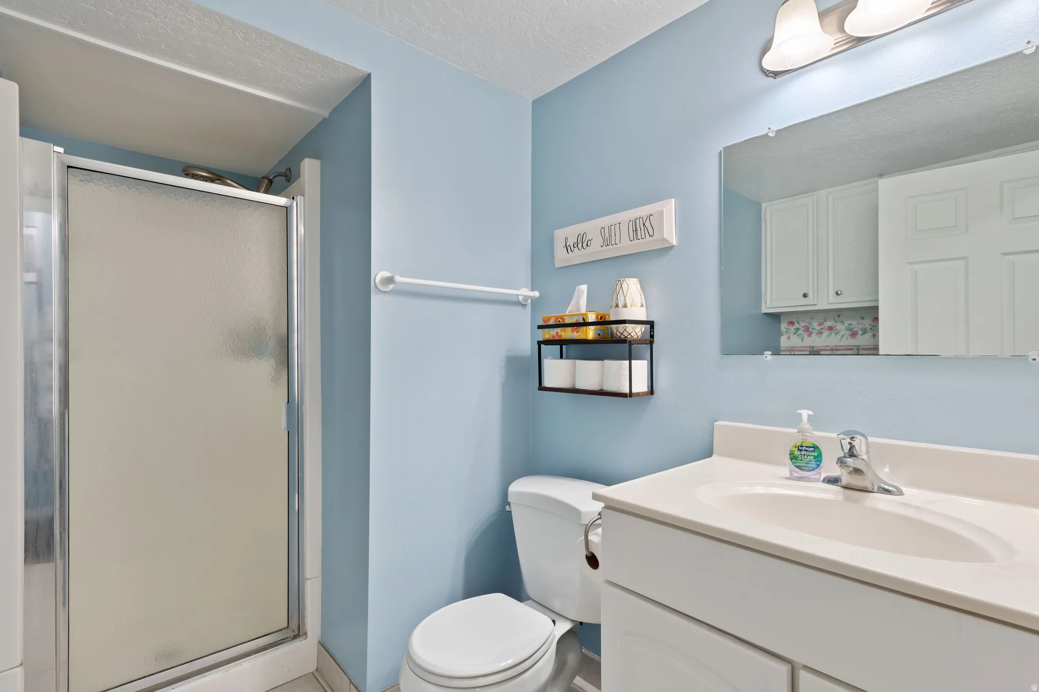 Bathroom with a stall shower, vanity, and a textured ceiling