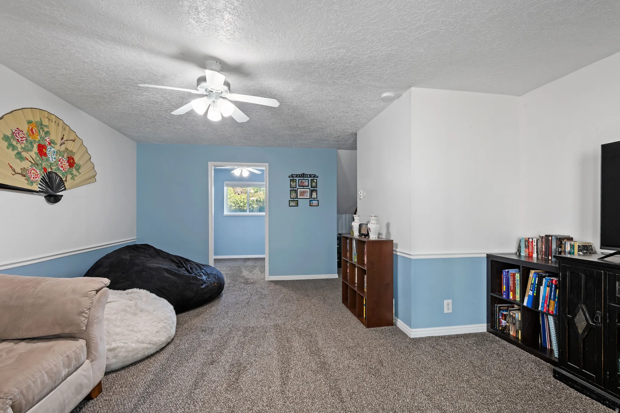 Living area with carpet, a textured ceiling, and ceiling fan