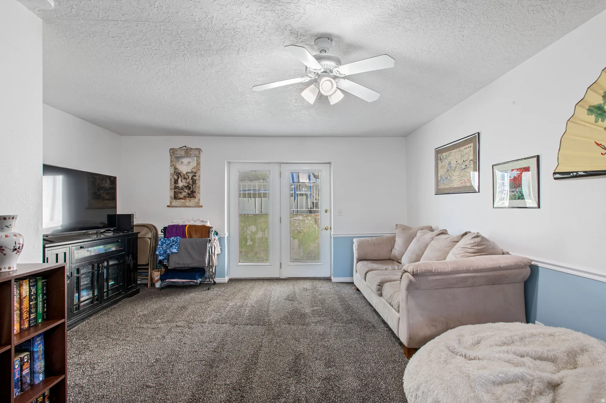 Carpeted living area with a textured ceiling and ceiling fan