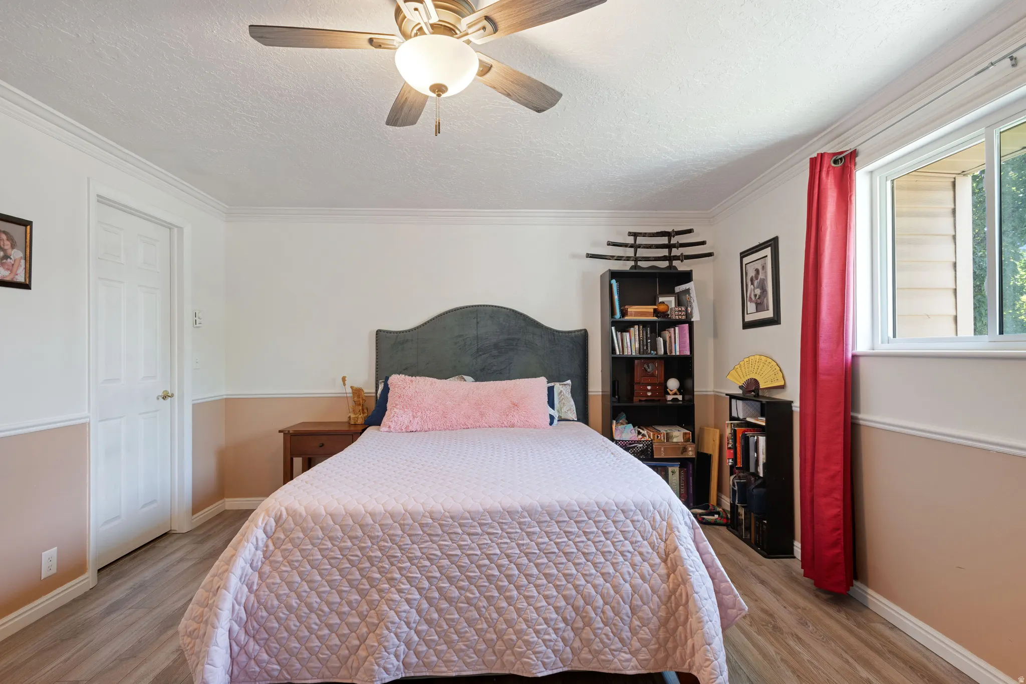 Bedroom with light wood-style floors, crown molding, a textured ceiling, and a ceiling fan