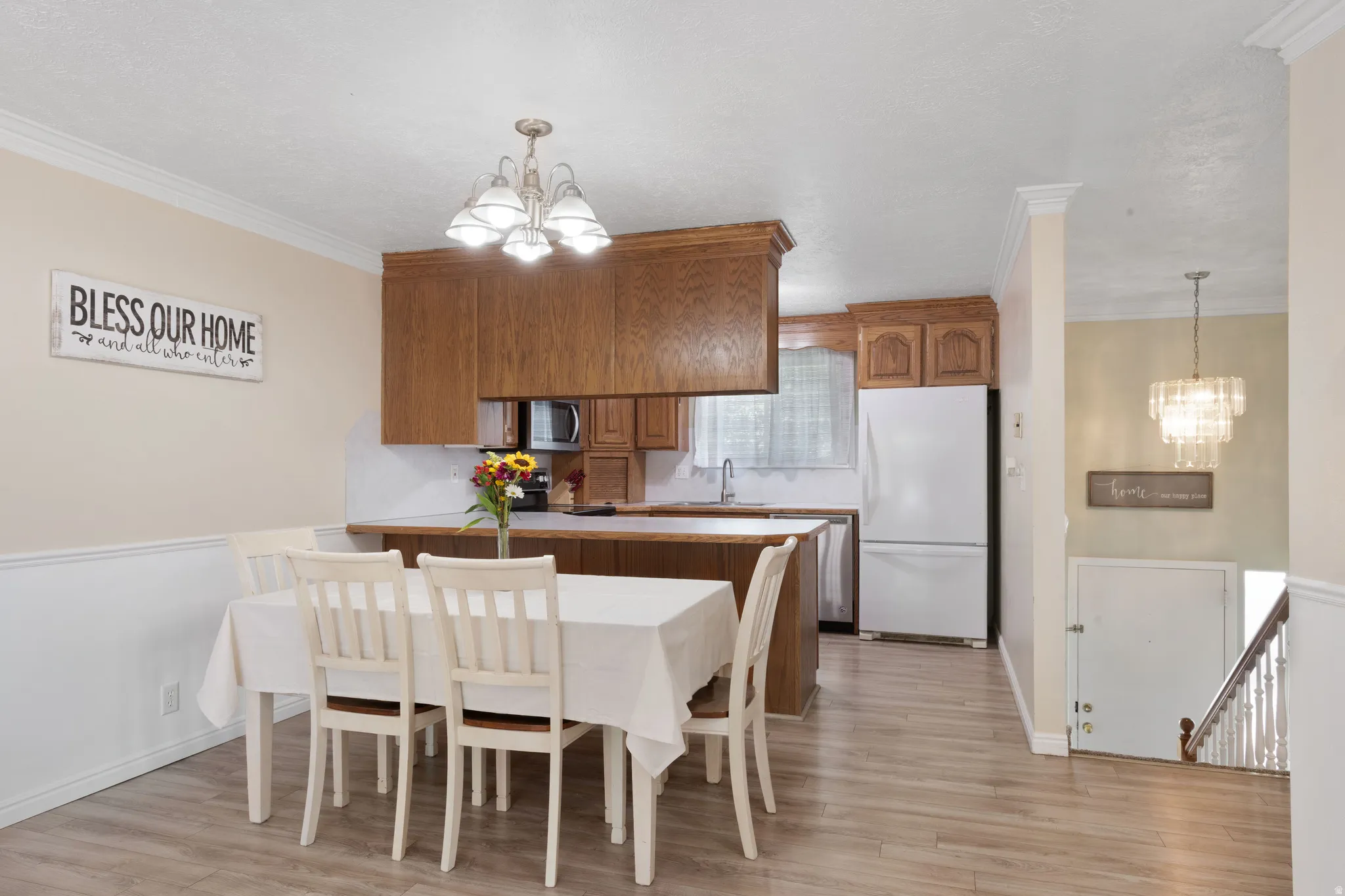Dining area with suspended lighting, ornamental molding, and light wood finished floors