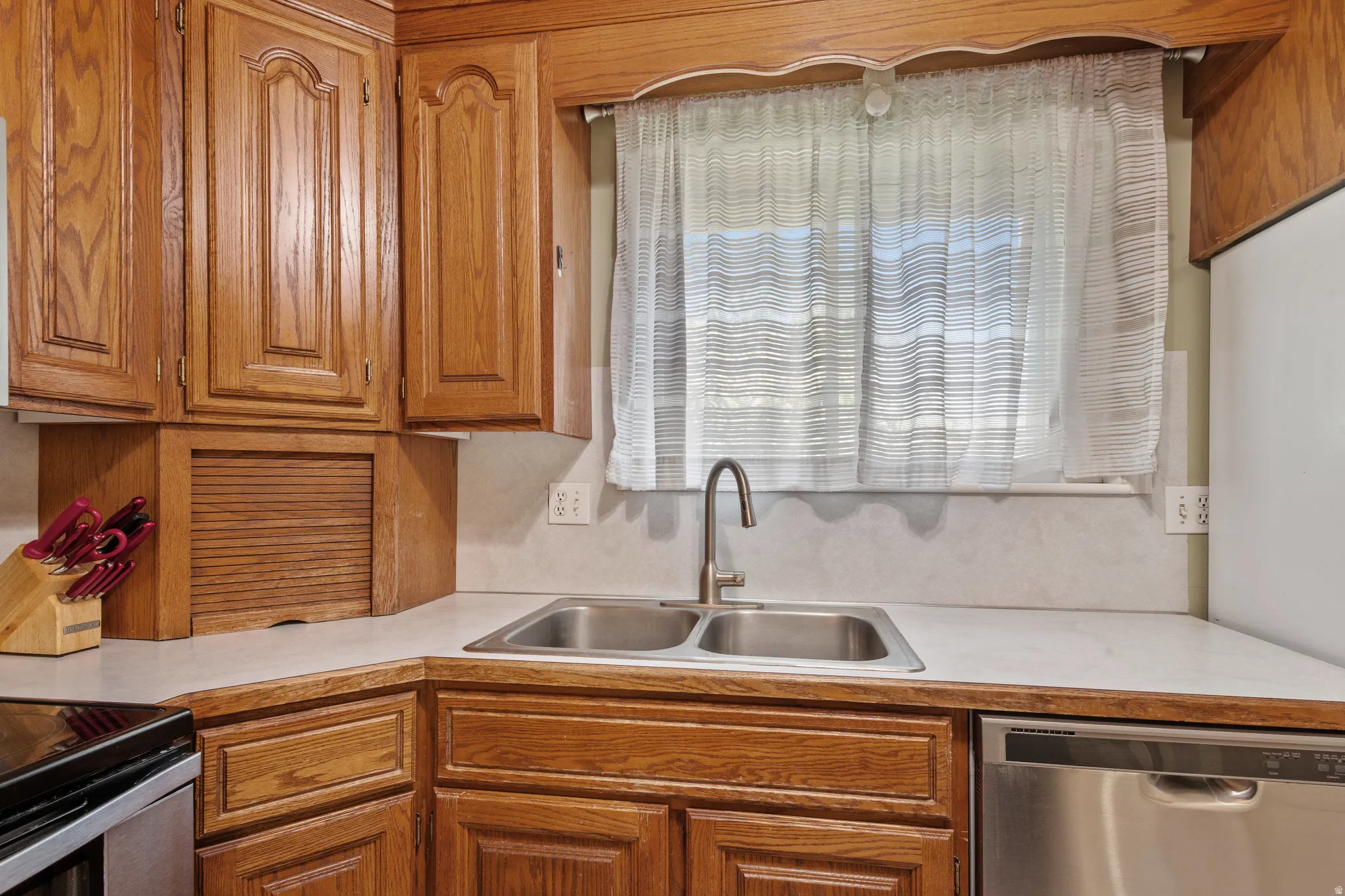 Kitchen featuring light countertops, stainless steel appliances, and wood finish cabinetry