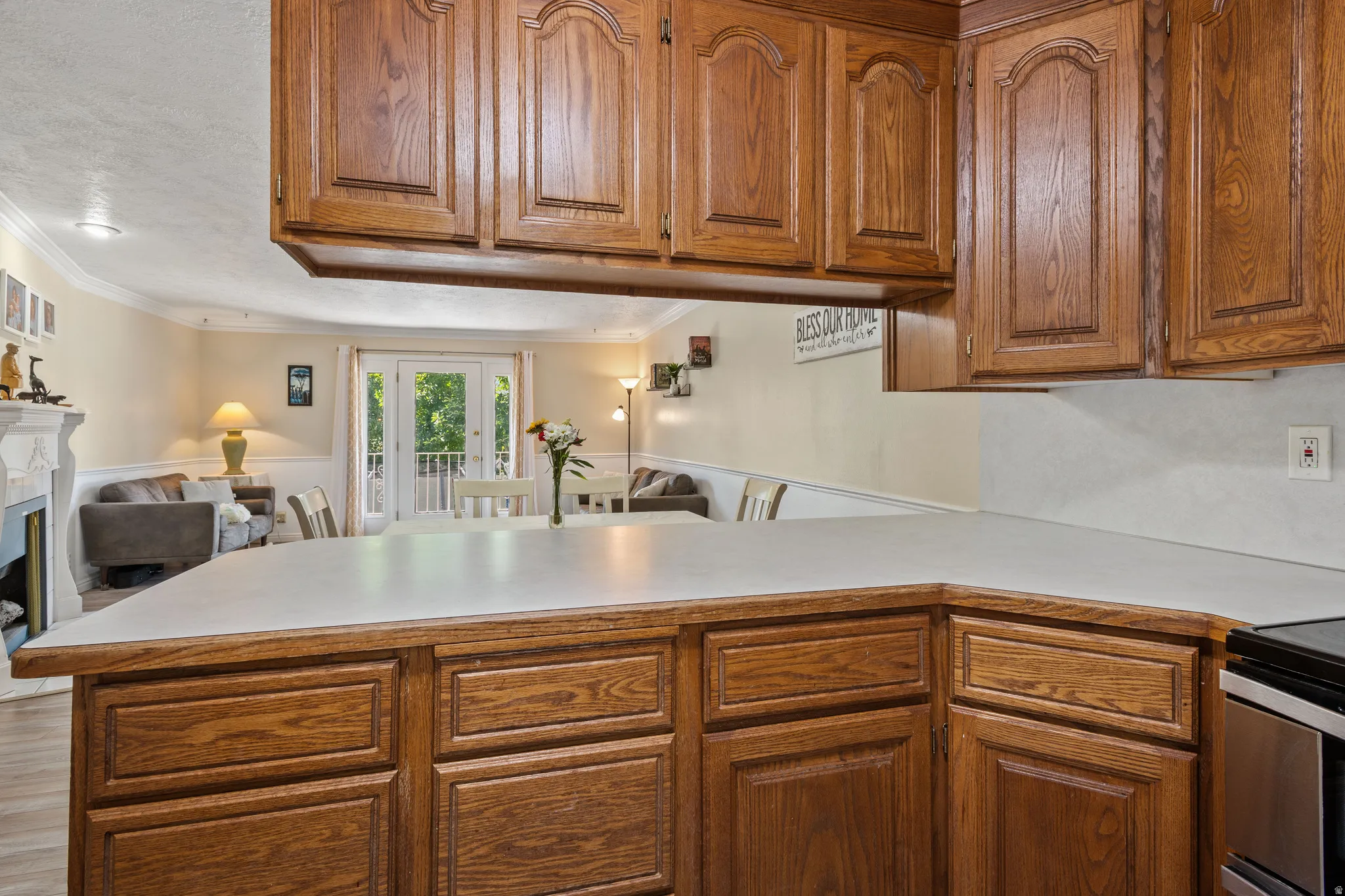 Kitchen featuring wood finish cabinets, light countertops, french doors, open floor plan, and ornamental molding
