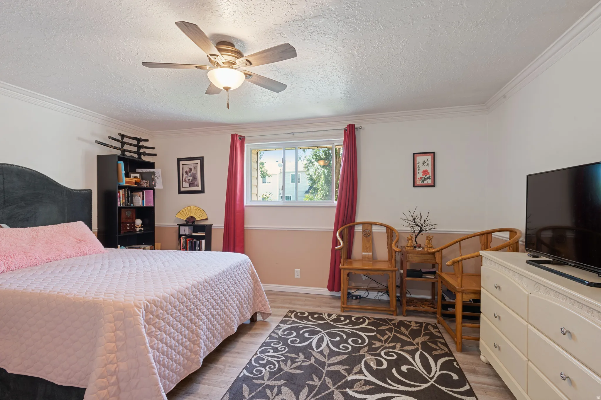 Bedroom featuring light wood-type flooring, ornamental molding, ceiling fan, and a textured ceiling