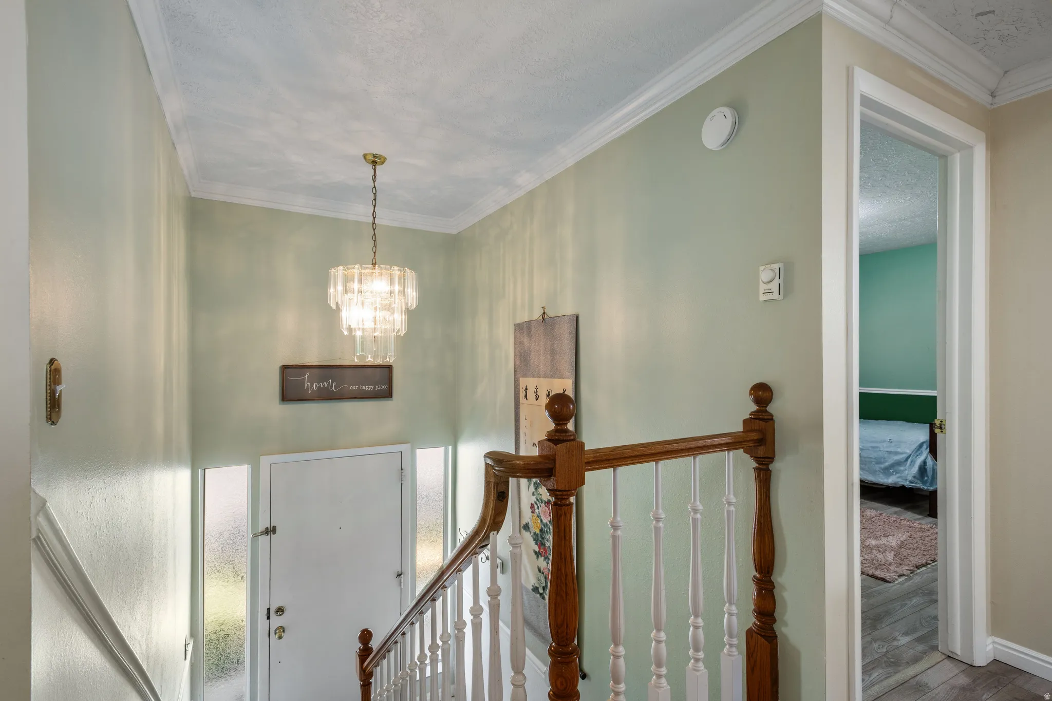 Entryway with crown molding, suspended lighting, wood finished floors, and a textured ceiling