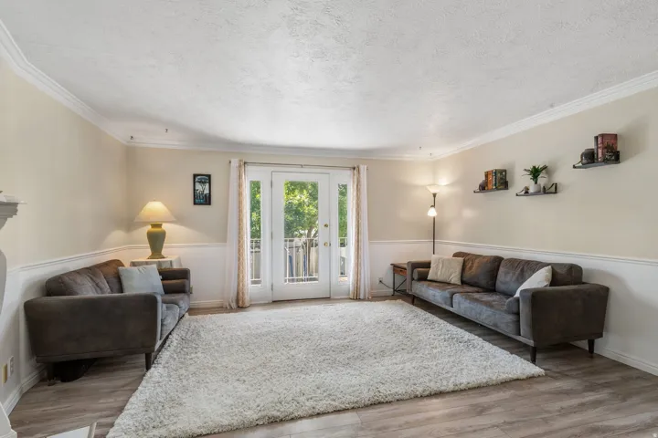 Living room with light wood-style flooring, a textured ceiling, and ornamental molding