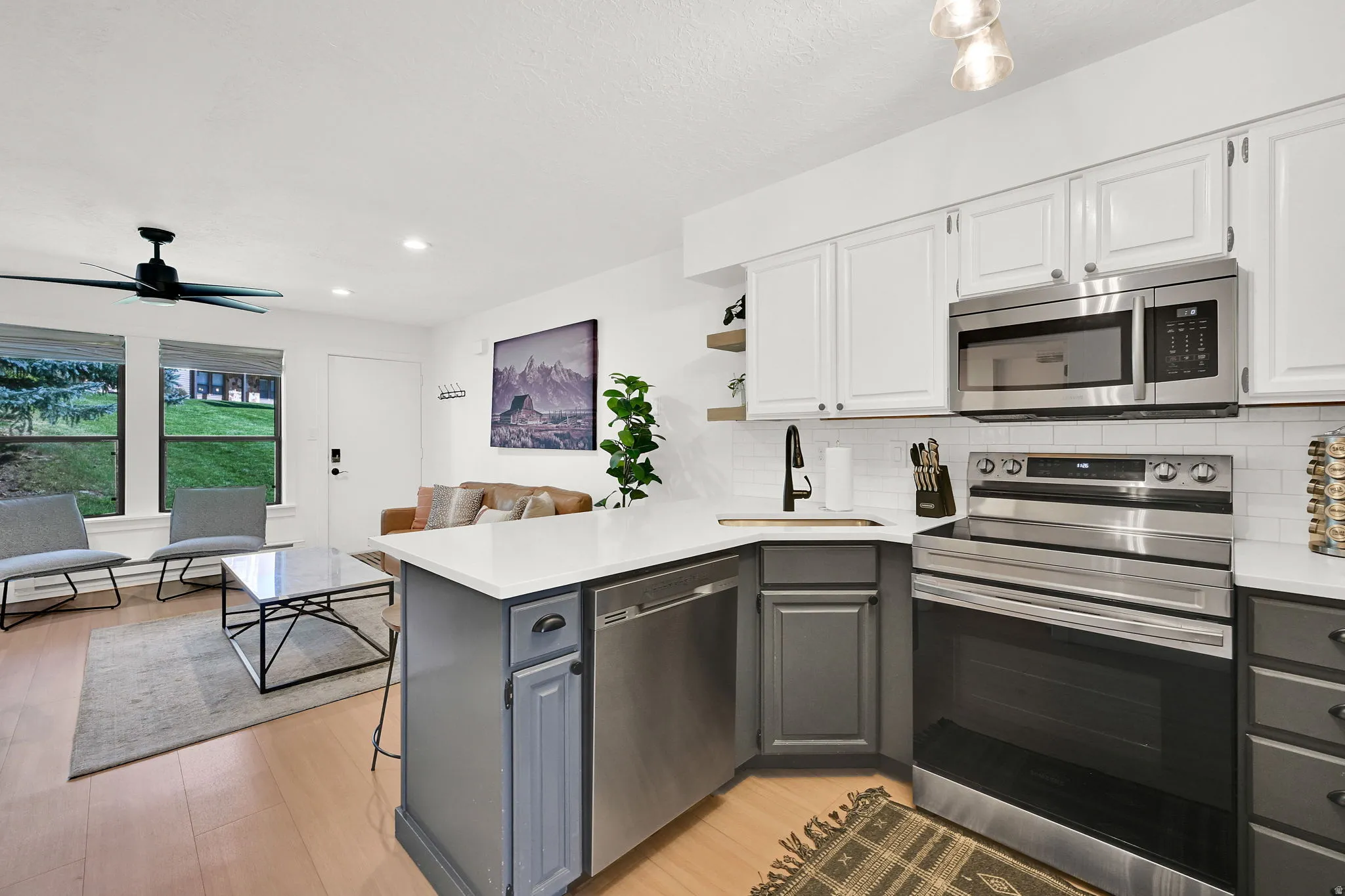 Kitchen featuring a peninsula, a breakfast bar, open shelves, stainless steel appliances, and two-tone cabinets.