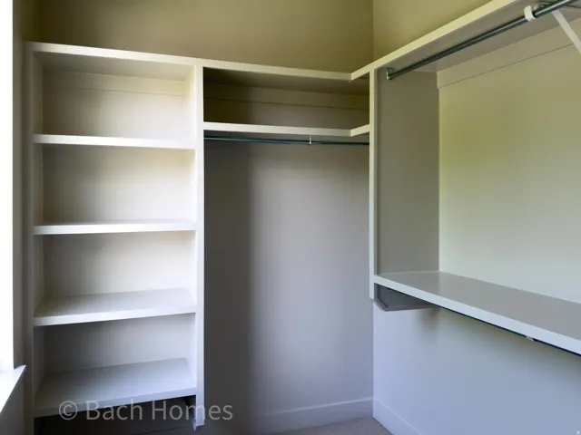 Built-in shelving, integrated hanging rods, and an overhead shelf provide storage solutions within this closet space