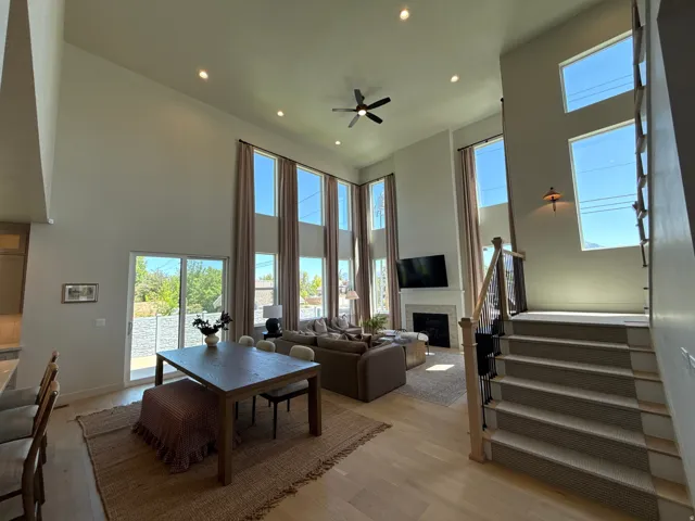 Vaulted ceilings with recessed lighting, an open-concept living area, a fireplace with a mantel, light wood-finish flooring, and a carpeted staircase with wood railings