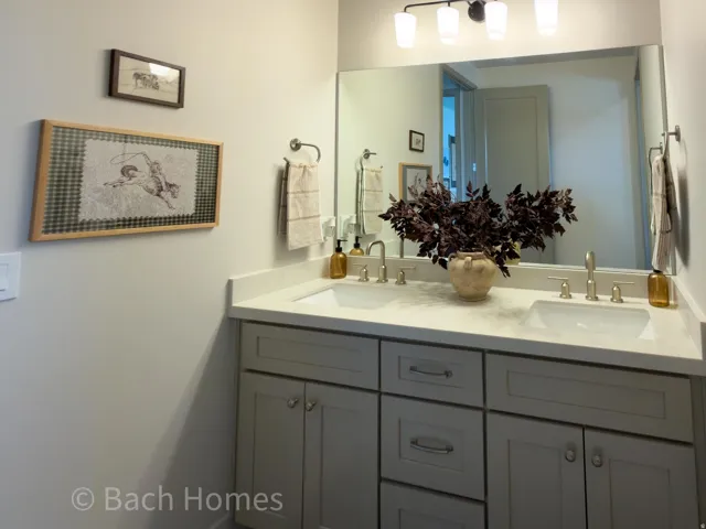 Dual vanity featuring light gray cabinetry, integrated sinks, brushed nickel fixtures, and a large wall-mounted mirror