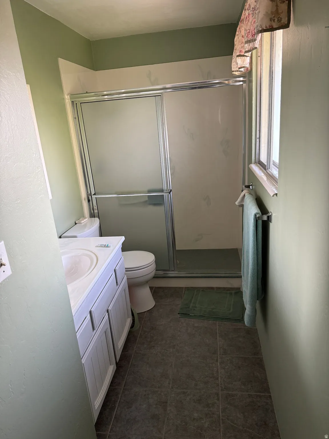 Full bathroom featuring vanity, a shower stall, and dark tile patterned flooring