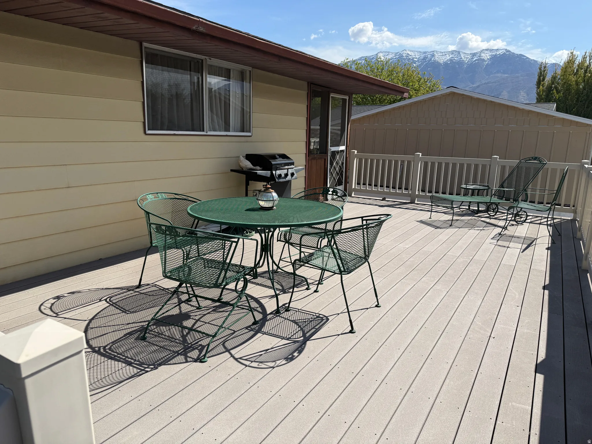 Deck with outdoor dining area, a mountain view, and grilling area