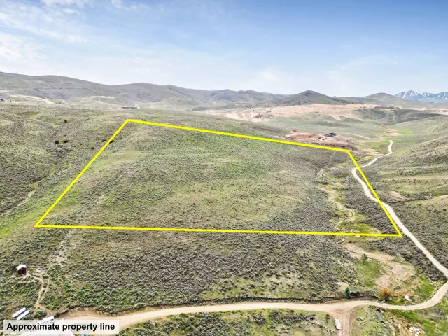Aerial view of sparsely populated area with property parcel outlined and a mountainous background