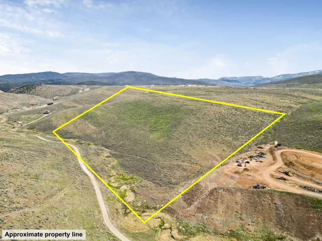 Aerial view of sparsely populated area featuring property boundaries highlighted and a mountain backdrop