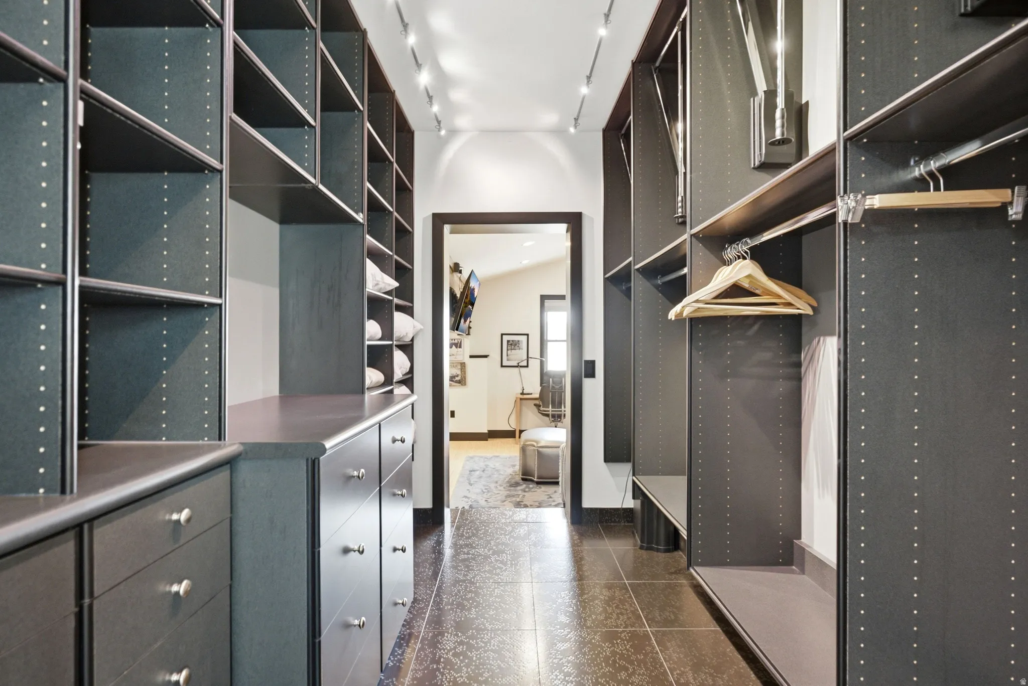 Custom closet system featuring dark wood-finish cabinetry, extensive shelving, integrated drawers with silver-tone hardware, and multiple hanging rods