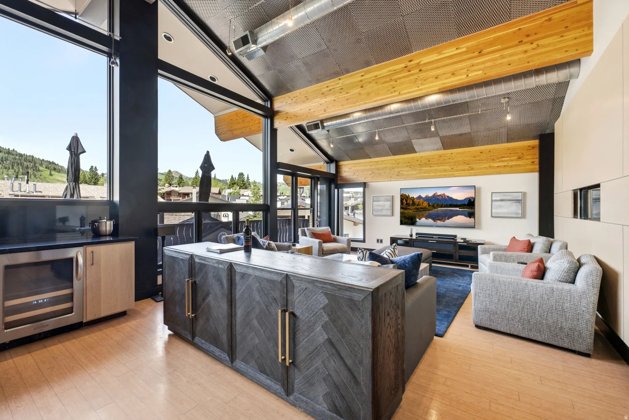 Open-concept living area featuring a vaulted ceiling with exposed wood beams and a metal grid finish